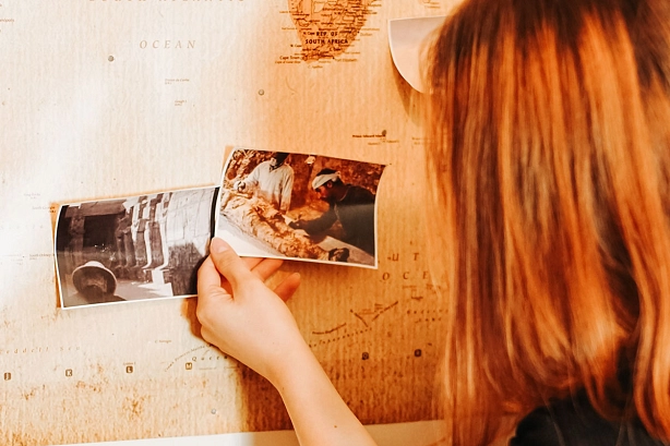 Escaperoom ein Mädchen steht vor einer Weltkarte und sieht sich Fotos an