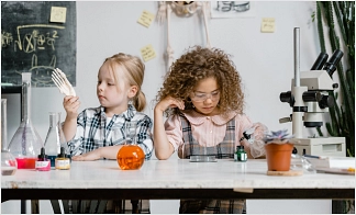 Zwei kleine Mädchen machen Experimente mit Reagenzgläsern und Flüssigkeiten